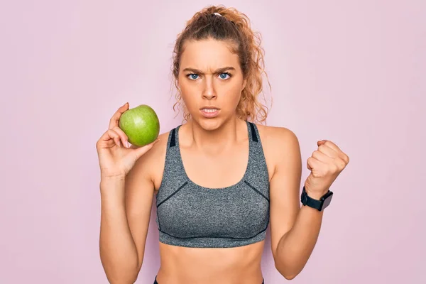 年轻美丽的金发女运动员 蓝眼睛 拿着健康的青苹果果实 怒气冲冲地大叫 疯狂地高喊 怒气冲冲 — 图库照片