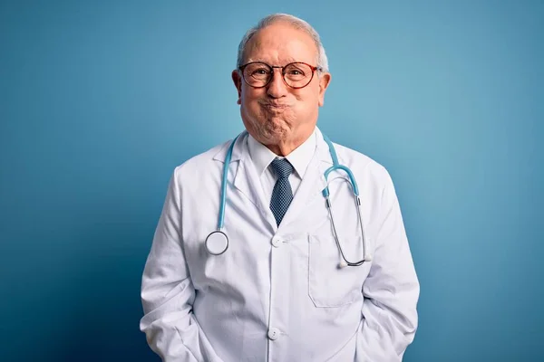 Starszy Siwy Lekarz Noszący Stetoskop Płaszcz Medyczny Niebieskim Tle Nadęty — Zdjęcie stockowe