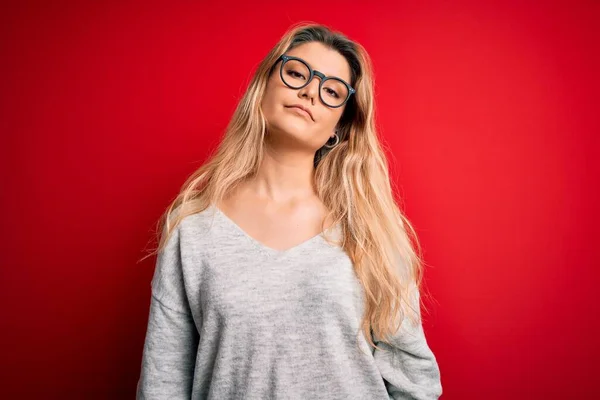 Jovem Mulher Loira Bonita Vestindo Suéter Óculos Sobre Fundo Vermelho — Fotografia de Stock