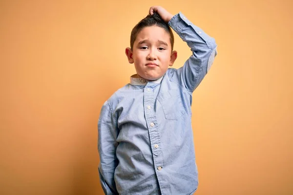 黄色の隔離された背景の上に立つエレガントなシャツを着ている若い男の子は混乱し 質問について疑問に思います 疑いもなく 頭の上で手で考えて 包括的概念 — ストック写真