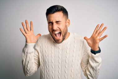 İzole edilmiş beyaz arka plan üzerinde dikilmiş kollarını kaldırmış ve gözlerini kapatmış heyecanlı bir şekilde başarı için deli ve çılgın bir kutlama yapan genç yakışıklı bir adam. Kazanan konsept