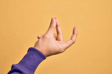 İzole edilmiş sarı arka planda parmaklarını gösteren beyaz bir gencin eli. Başarı için parmaklarını şıklatıyor, kolay ve eliyle sembolü tıklatıyor.