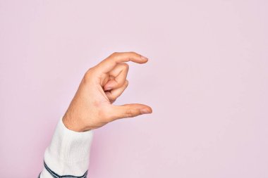 İzole edilmiş pembe arka plan üzerinde parmaklarını gösteren beyaz bir adamın eli. Görünmez bir şeyi alıp, parmaklarıyla uzayı gösteren bir nesneyi tutuyor.