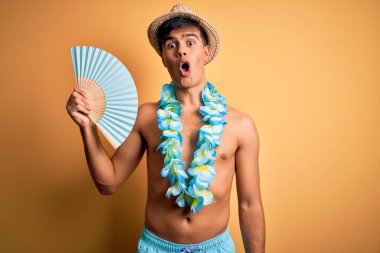 Tatildeki genç turist mayo giyiyor ve Hawai çiçekleri el ele tutuşuyor. Şok olmuş şaşkınlık dolu bir yüz ifadesinden korkuyor ve heyecanlanıyor.