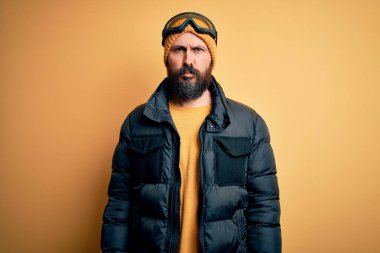 Sakallı, kar maskesi takmış, kar maskesi takmış, kayak yapan yakışıklı, kel bir kayakçı. Depresyonda ve endişe içinde, sinirli ve korkmuş. Üzücü ifade.