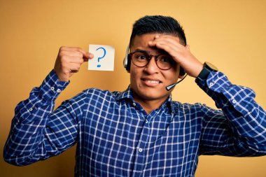 Genç latin çağrı merkezi ajanı elinde soru işaretli hatırlatma kâğıdıyla kulaklık takıyor. Yüzünde utanç ve şaşkınlık ifadesi var. Öfkeli ve hayal kırıklığına uğramış. Hata için korku ve üzüntü.