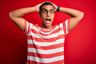 Genç, yakışıklı, Afro-Amerikalı, sıradan çizgili tişört ve gözlük takan, elleri kafasında çılgın, korkmuş ve ağzı açık bir şekilde şok geçirmekten korkan ve şaşırmış bir adam.