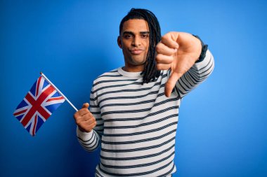 Genç Afro-Amerikan vatansever bir adam elinde Birleşik Krallık bayrağı, kızgın bir yüz, olumsuz bir işaret baş parmakları aşağıda, reddedilme konsepti var.