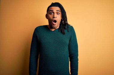 Genç, yakışıklı, Afro-Amerikan Afrikalı, rastalı yeşil kazaklı, korkmuş ve şok olmuş bir adam..