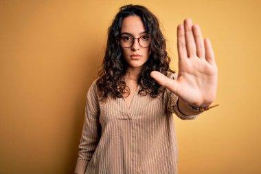 Kıvırcık saçlı, çizgili tişörtlü ve sarı arka planda gözlüklü güzel bir kadın avucunun içi gibi şarkı söylemeyi kesiyor. Yüzünde olumsuz ve ciddi bir jest olan uyarı ifadesi.