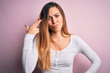 Genç, güzel, sarışın, mavi gözlü, pembe arka planda beyaz tişört giyen, silah gibi el ve parmakları işaret eden, intihar eden bir kadın..