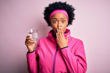 Kıvırcık saçlı genç Afrikalı Afro Amerikalı sporcu. Bir bardak su içti. Ağzını kapattı.