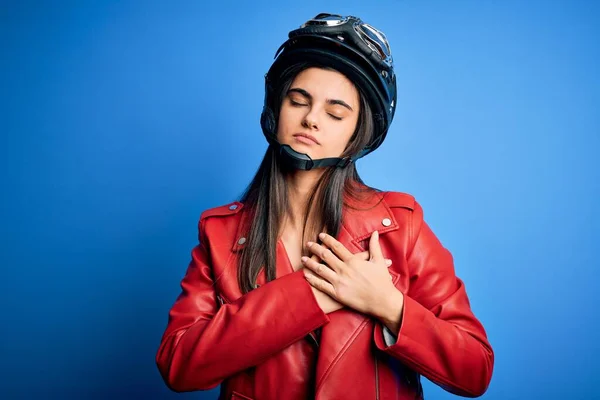 若い美しいブルネットのオートバイのヘルメットとジャケットを身に着けているオートバイの女性は 目を閉じて胸に手で笑顔と顔に感謝のジェスチャー 健康コンセプト — ストック写真