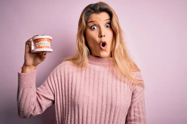 Jovem Bela Mulher Loira Segurando Plástico Dentadura Sobre Fundo Rosa — Fotografia de Stock