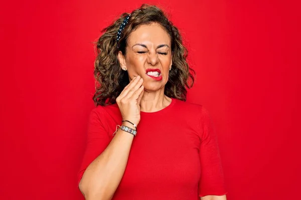 中年老年黑发女人 身穿休闲装 站在红色背景下 手牵手触摸嘴 因为牙齿疼痛或牙病而有痛苦的表情 牙科医生 — 图库照片