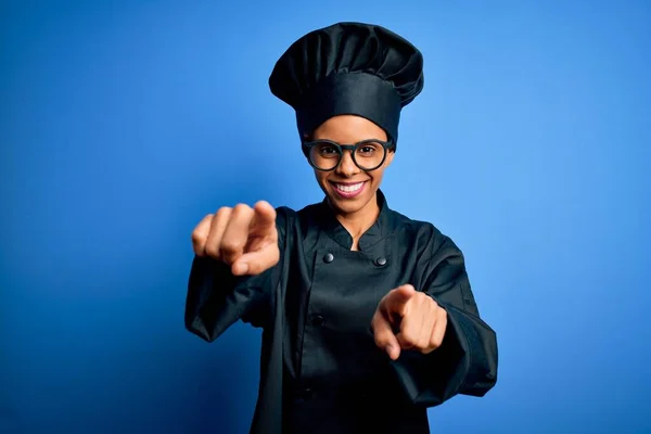 年轻的非洲女厨师身穿炊具制服 头戴蓝色背景的帽子 手指指向你和相机 面带微笑 面带微笑 面带微笑 — 图库照片
