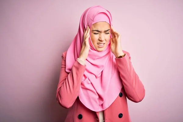 年轻美丽的女孩戴着穆斯林头巾站在孤立的粉红色背景上 手扶着头疼 因为压力 痛苦的偏头痛 — 图库照片