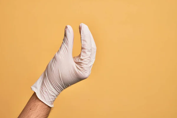 Mão Jovem Caucasiano Com Luva Médica Sobre Fundo Amarelo Isolado — Fotografia de Stock