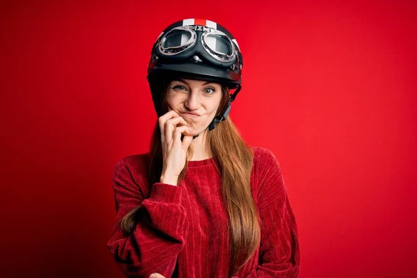 若いです美しいです赤毛Motocystist女性身に着けています本ヘルメット以上赤背景思考疲れていると退屈でうつ病問題とともに交差腕 — ストック写真