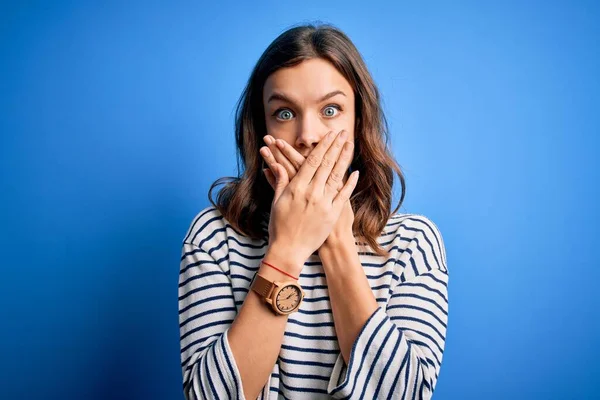 青い隔離された背景の上に立つカジュアルなセーターを着た若い美しいブロンドの女の子は 間違いのために手で口をカバーショックを受けました 秘密概念 — ストック写真