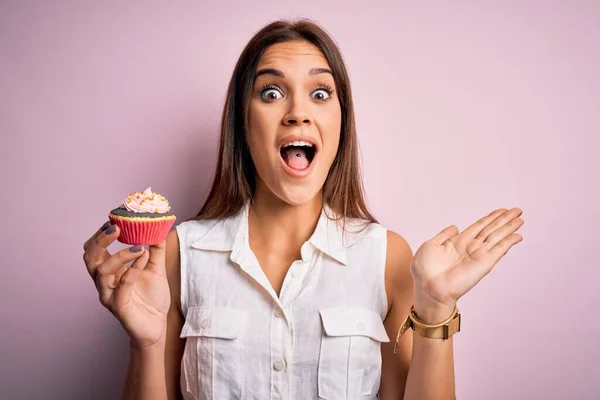 Ung Vacker Brunett Kvinna Äter Choklad Cupcake Över Isolerad Rosa — Stockfoto