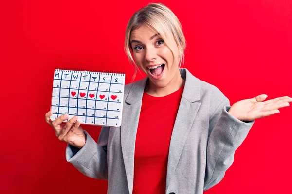 Mooie Blonde Vrouw Controleren Menstruatie Holding Periode Kalender Rode Achtergrond — Stockfoto
