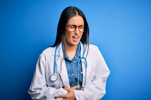 胃の上に手で青い背景に聴診器や眼鏡をかけている若い美しい医師の女性は吐き気 痛みを伴う病気が体調を崩します アチェの概念 — ストック写真
