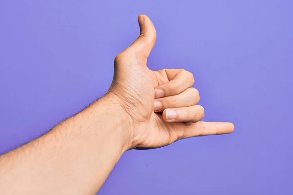 用手指在孤立的紫色背景上握住高加索年轻人的手 表示夏威夷沙卡式的问候手势 电话和通信符号 — 图库照片