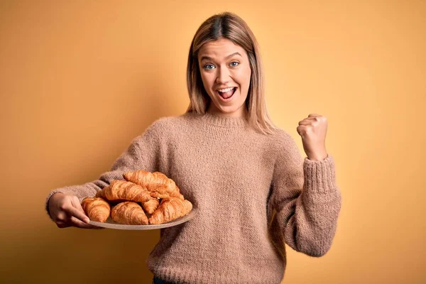 Young Beautiful Woman Holding Plate Croissants Isolated Yellow Background Screaming — Stock Photo, Image