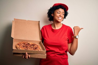 Kıvırcık saçlı, İtalyan pizzalı ve gülümseyen yüzüyle yüzünü gösteren Afro-Amerikan bir kadın.