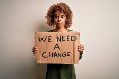 Genç Afro-Amerikan aktivist kadın değişim istiyor. Elinde afiş, akıllı suratında kendinden emin bir ifadeyle ciddi ciddi düşünüyor.