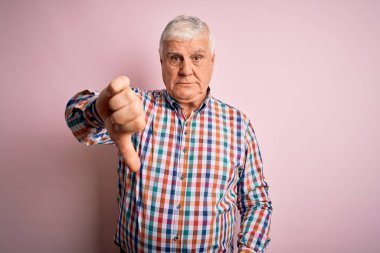 Üst düzey yakışıklı beyaz adam, pembe arka plan üzerine gündelik tişört giyiyor mutsuz, kızgın, reddedilmiş ve olumsuz hareketler sergiliyor. Kötü ifade.