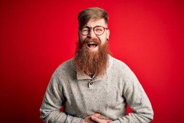 Sakallı, kızıl saçlı, kırmızı arka planda gözlüklü, sıradan bir İrlandalı yakışıklı adam..