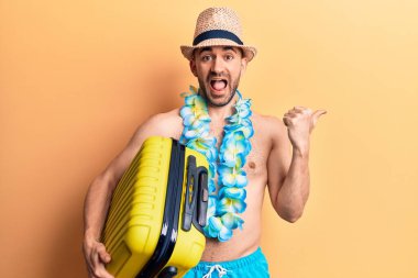 Mayo giyen genç ve kel bir adam ve elinde kamara çantası olan Hawai zambağı başparmağını yukarı kaldırarak ağzı açık bir şekilde gülümsüyor. 