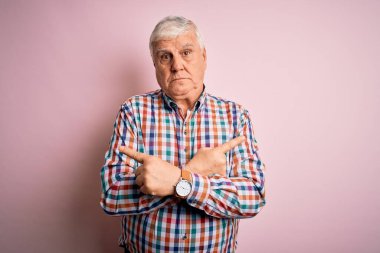 Üst düzey yakışıklı, parlak gömlekli, soyutlanmış pembe arka planda, her iki tarafı da parmaklarıyla gösteren, farklı yönlü, farklı renkte bir adam.
