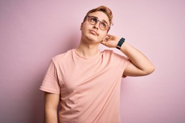 İzole edilmiş pembe arka planda duran ve soru soran sıradan tişörtlü genç ve yakışıklı kızıl saçlı adam. Şüpheyle kararsız, kafa kafaya düşünerek. Düşünceli kavram.