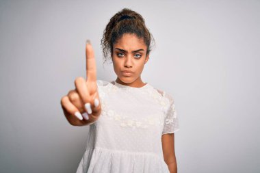 Genç, güzel, Afro-Amerikalı bir kız. Sıradan tişörtler giyiyor. Beyaz arka plan üzerinde duruyor.