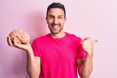 Genç ve yakışıklı bir adam, beyni soyutlanmış pembe arka planda tutan ve ağzı açık gülümseyen bir adam istiyor.