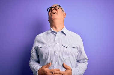Orta yaşlı, beyaz, çizgili gömlek ve mor arka planda gözlük takan, midesi bulanan, acı verici bir hastalıktan dolayı midesi bulanan, orta yaşlı, beyaz bir adam. Ache kavramı.