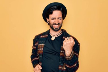 Genç, yakışıklı, bohem, hippi tarzı giyinmiş ve bohem şapkalı bir adam kolları havada ve gözleri kapalı bir şekilde başarıyı kutluyor. Kazanan konsept.