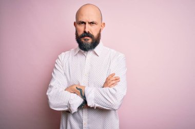 Sakallı, zarif gömlekli yakışıklı, pembe arka plan kuşkucu ve gergin, yüzünde çapraz kollu tasvip etmeyen bir ifade var. Negatif kişi.