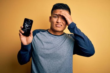 Kırık akıllı telefon tutan genç, yakışıklı Latin bir adam kafasında kırık bir ekran gösteriyor. Utanç ve şaşkınlık dolu bir yüz ifadesi var. Kızgın ve sinirli. Hata için korku ve üzüntü.