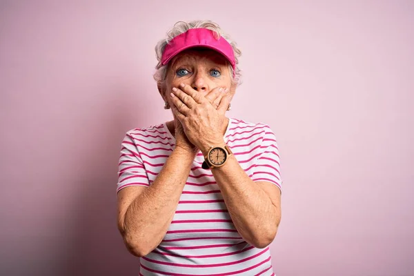 身穿运动帽站在孤立的粉色背景上的漂亮的大运动型女人因犯错而用双手捂住了嘴 秘密概念 — 图库照片
