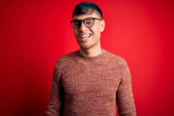 Mladý Pohledný Hispánec Nosí Nerd Brýle Přes Červené Pozadí Mrkající — Stock fotografie