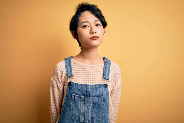 Mladá Krásná Asijská Dívka Neformální Džínové Kombinéze Přes Izolované Žluté — Stock fotografie