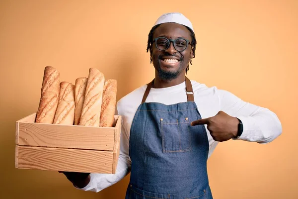 年轻的非洲裔美国面包师 头戴围裙 手里拿着装有自制面包的木盒 满脸惊讶地指着自己 — 图库照片