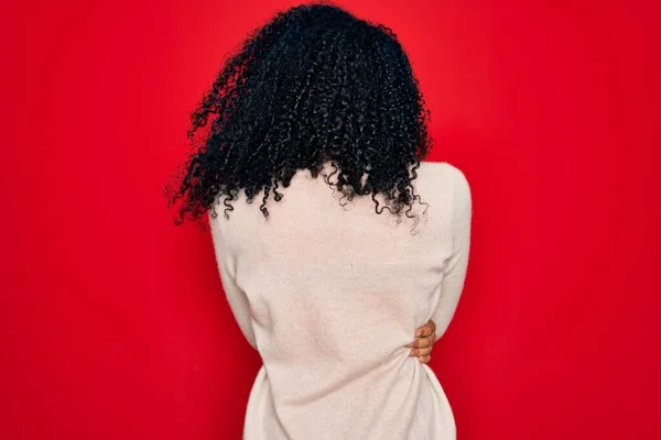 年轻的非洲裔美国卷曲女人 身穿红色背景的宽松毛衣 手挽手向后看去 — 图库照片
