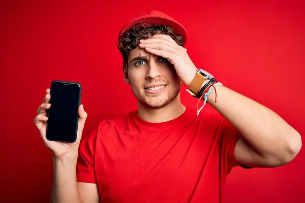 Kıvırcık Saçlı Şapkalı Kırmızı Arka Planda Akıllı Telefon Tutan Genç — Stok fotoğraf