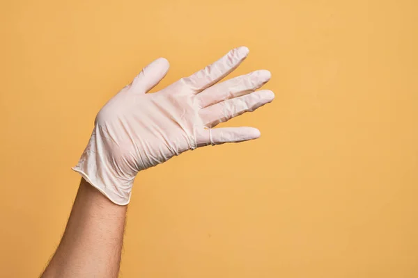 Mão Jovem Caucasiano Com Luva Médica Sobre Fundo Amarelo Isolado — Fotografia de Stock