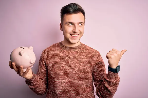 Fiatal Jóképű Kaukázusi Férfi Tartja Malac Bank Megtakarítás Felett Rózsaszín — Stock Fotó